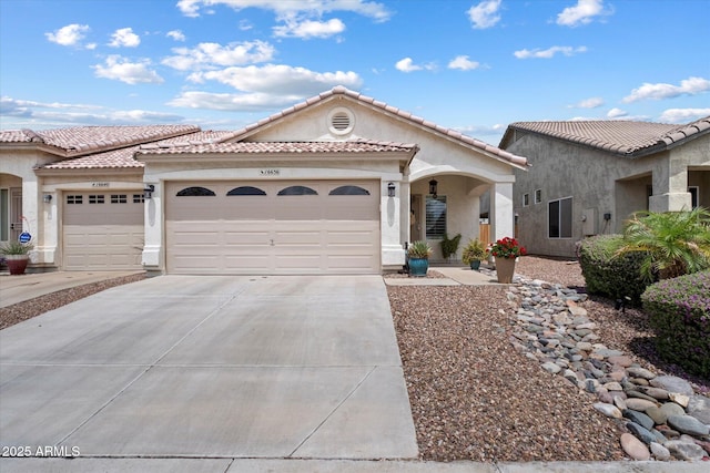 mediterranean / spanish-style home with a garage, concrete driveway, stucco siding, and a tiled roof