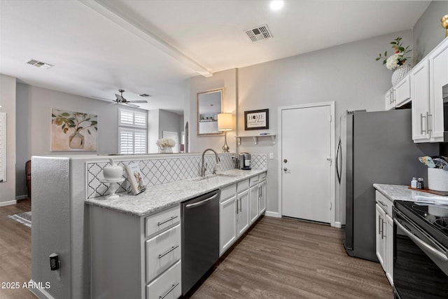 kitchen featuring stainless steel dishwasher, a sink, a peninsula, black / electric stove, and dark wood-style flooring