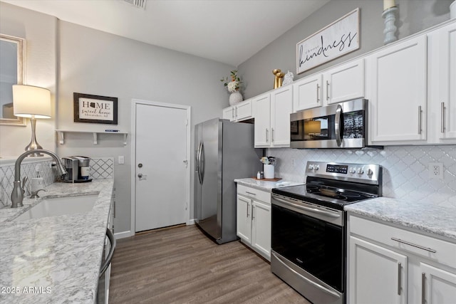 kitchen with appliances with stainless steel finishes, a sink, tasteful backsplash, and white cabinets