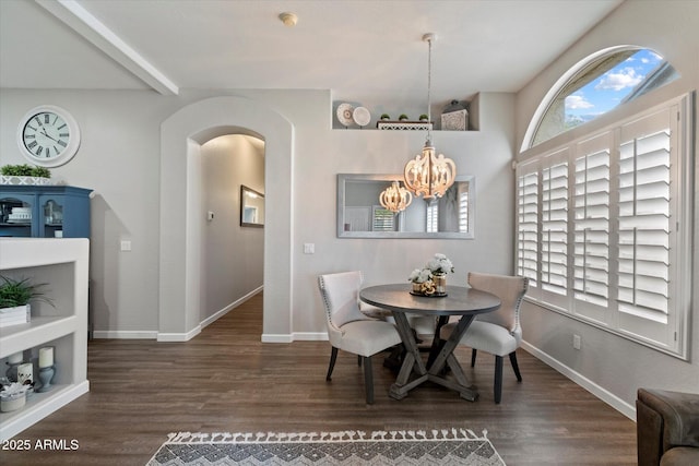 dining area featuring arched walkways, wood finished floors, a chandelier, and baseboards