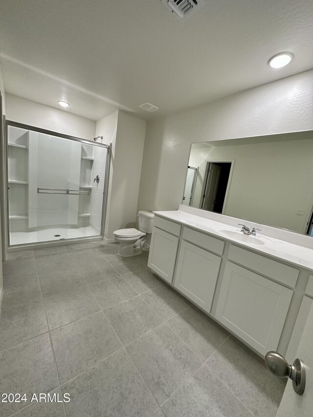 bathroom with tile patterned floors, vanity, toilet, and a shower with shower door