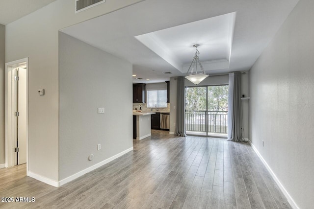815 E Rose Ln Unit 105, Phoenix, AZ 85014 - unfurnished living room with visible vents, baseboards, light wood-style flooring, and a raised ceiling