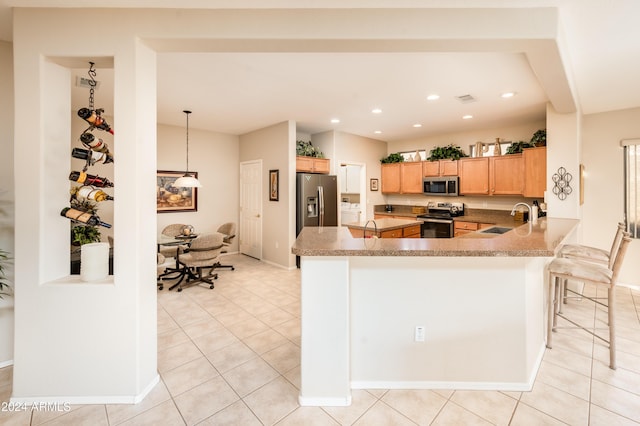 kitchen featuring a breakfast bar, sink, decorative light fixtures, kitchen peninsula, and stainless steel appliances