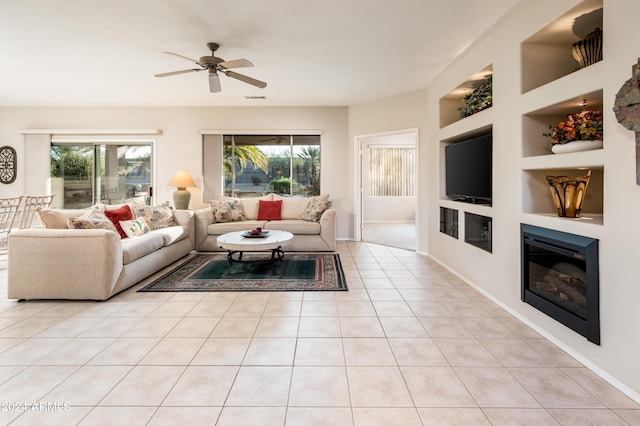 living room featuring built in shelves, ceiling fan, and light tile patterned flooring