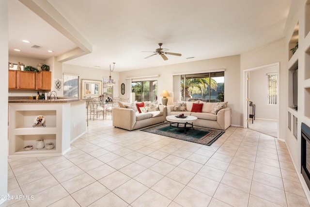 tiled living room featuring built in shelves, ceiling fan, and sink