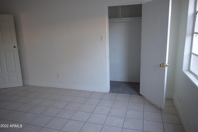 unfurnished bedroom featuring light tile flooring and a closet