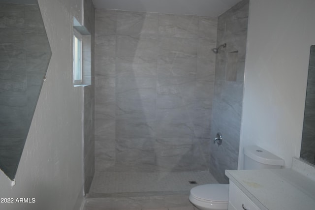 bathroom featuring toilet, vanity, and a tile shower