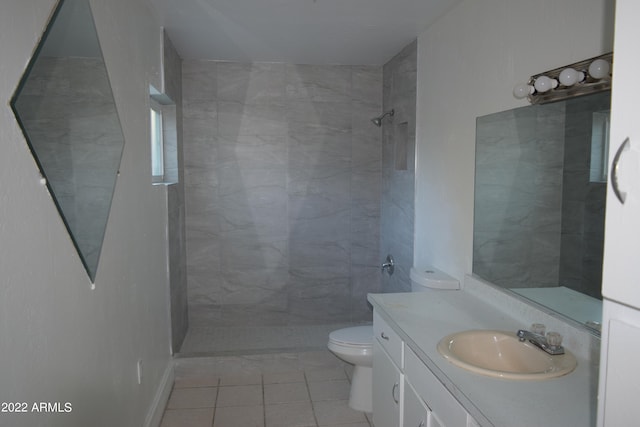 bathroom featuring toilet, a tile shower, tile floors, and vanity with extensive cabinet space