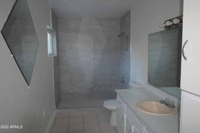 bathroom featuring toilet, oversized vanity, tile flooring, and a tile shower