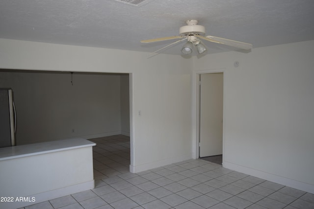 tiled empty room with ceiling fan and a textured ceiling