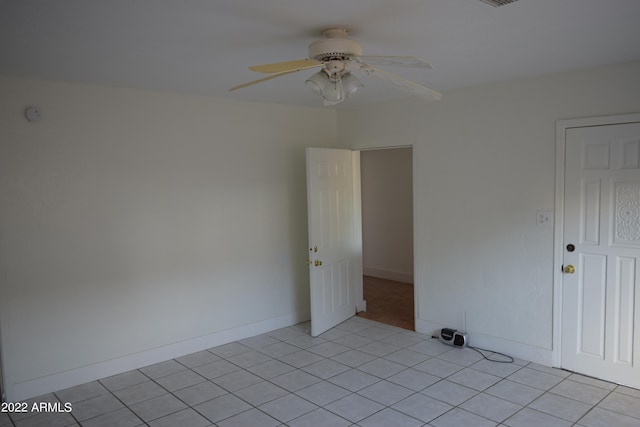 spare room featuring light tile floors and ceiling fan