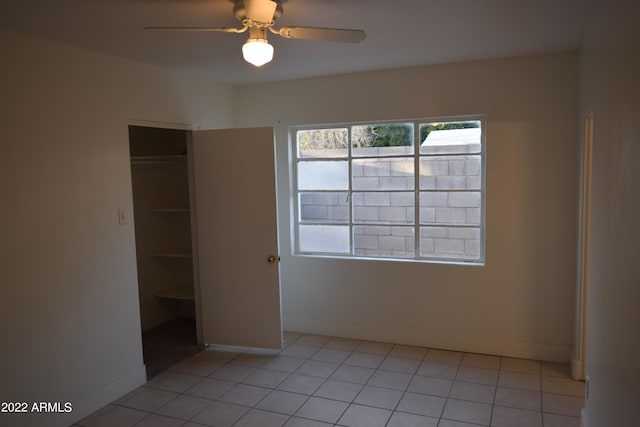 unfurnished bedroom with light tile flooring, a closet, and ceiling fan