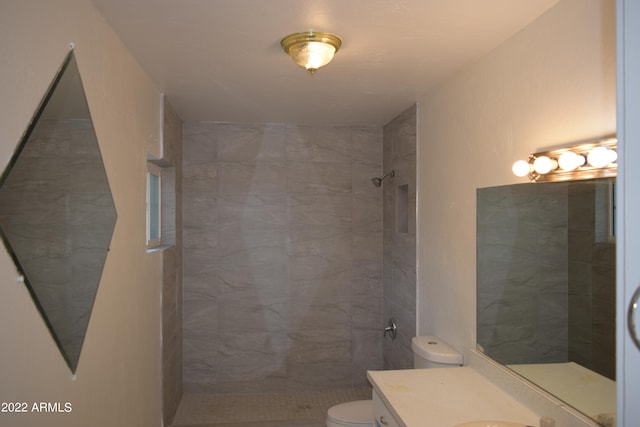 bathroom featuring toilet, vanity, and tiled shower