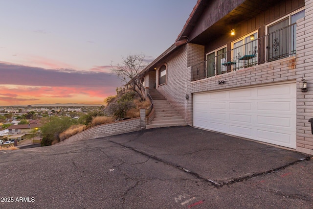 11237 N 15th Ln, Phoenix, AZ 85029 - property exterior at dusk featuring driveway, brick siding, a garage, a balcony, and stairs