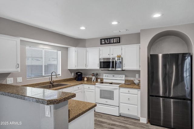 kitchen with a peninsula, white cabinets, stainless steel appliances, and a sink