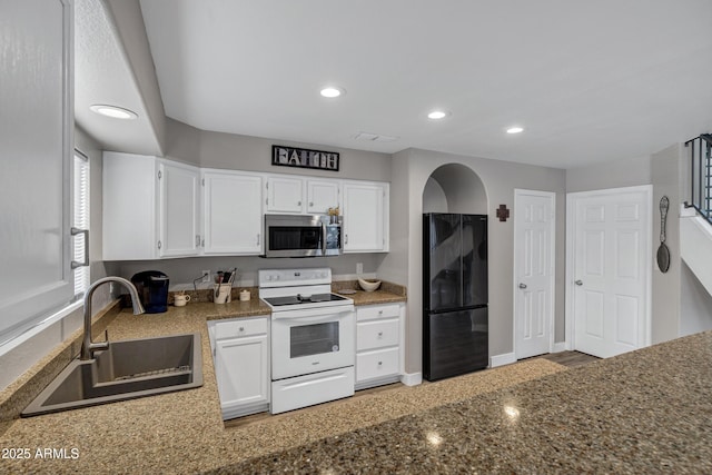 kitchen with white electric stove, a sink, white cabinets, freestanding refrigerator, and stainless steel microwave