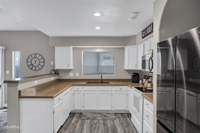 kitchen featuring visible vents, appliances with stainless steel finishes, a peninsula, white cabinetry, and a sink