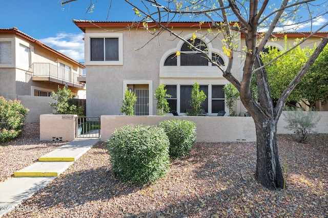 view of front facade with a fenced front yard, a gate, and stucco siding