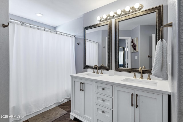 bathroom featuring wood finished floors, a sink, a shower with shower curtain, and double vanity