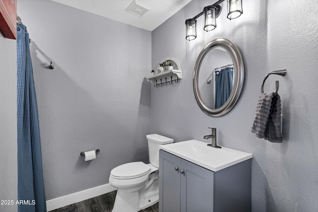 full bathroom featuring toilet, wood finished floors, vanity, visible vents, and baseboards