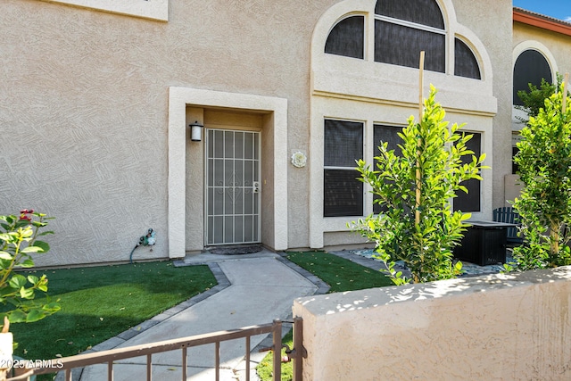 property entrance featuring a tile roof, fence, and stucco siding