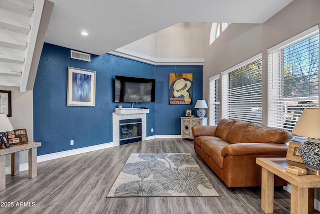 living room with baseboards, visible vents, a tile fireplace, wood finished floors, and recessed lighting