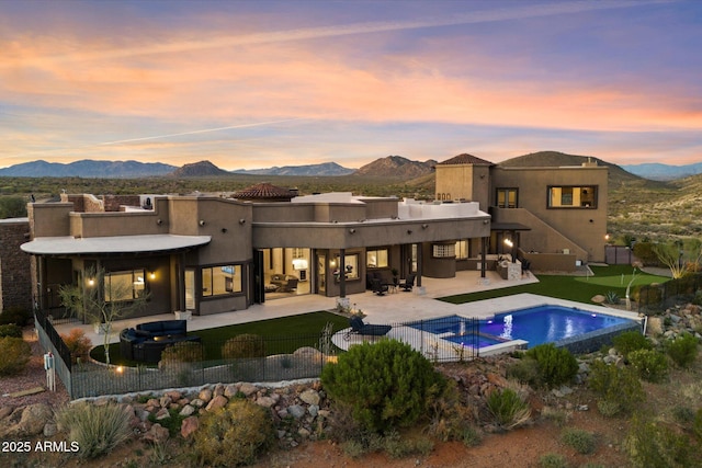 back of property with a mountain view, a fenced backyard, and a patio area