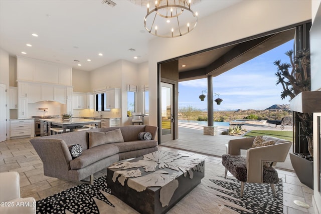 living room with a notable chandelier, stone tile floors, a towering ceiling, and recessed lighting