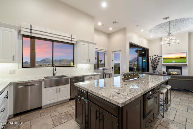 kitchen featuring a sink, stone tile floors, visible vents, and stainless steel dishwasher