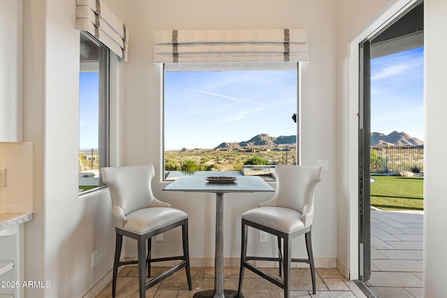 dining area featuring baseboards, a mountain view, and plenty of natural light