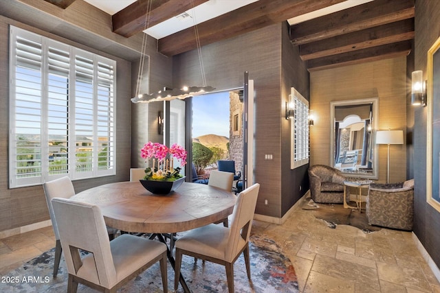 dining area featuring baseboards, beam ceiling, and stone tile floors
