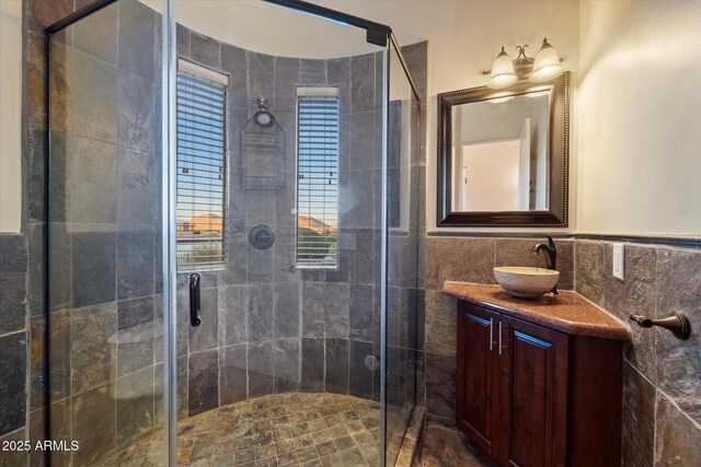 bathroom featuring a stall shower, vanity, and tile walls