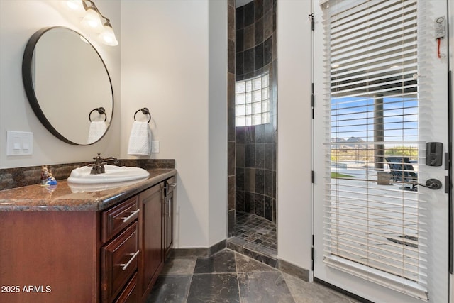 bathroom with marble finish floor, baseboards, a walk in shower, and vanity