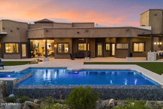 back of house with a pool with connected hot tub, a patio area, stucco siding, outdoor dry bar, and ceiling fan