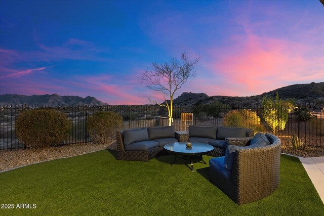 yard at dusk with a fenced backyard, a mountain view, and outdoor lounge area