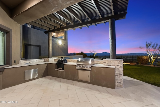 view of patio featuring a pergola, grilling area, an outdoor kitchen, and fence