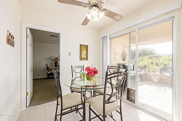 tiled dining room with a textured ceiling, a wealth of natural light, and ceiling fan