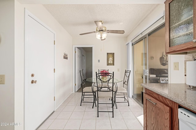 dining space featuring ceiling fan, light tile patterned flooring, and a textured ceiling