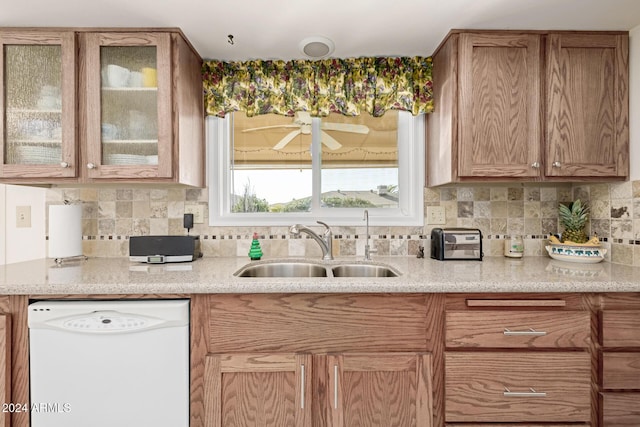 kitchen featuring white dishwasher, sink, ceiling fan, light stone countertops, and tasteful backsplash