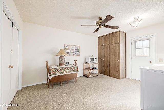 sitting room featuring a textured ceiling, washer / clothes dryer, ceiling fan, and light colored carpet