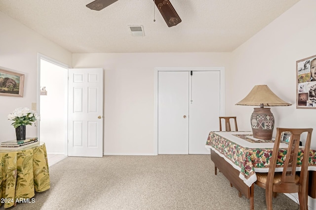 interior space featuring ceiling fan, light colored carpet, and a textured ceiling