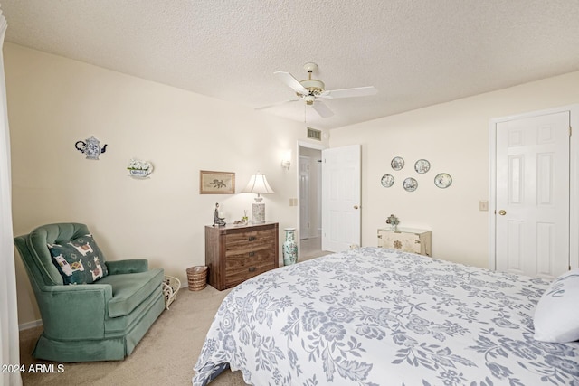 bedroom featuring a textured ceiling, light colored carpet, and ceiling fan