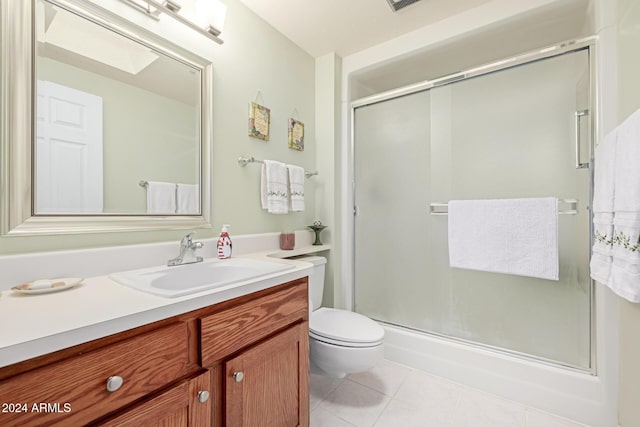 bathroom featuring tile patterned flooring, vanity, walk in shower, and a skylight