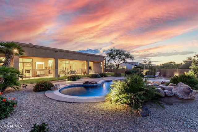 pool at dusk featuring a patio, a fenced in pool, and fence