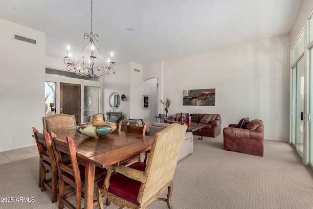 dining room with visible vents, arched walkways, a notable chandelier, and light carpet