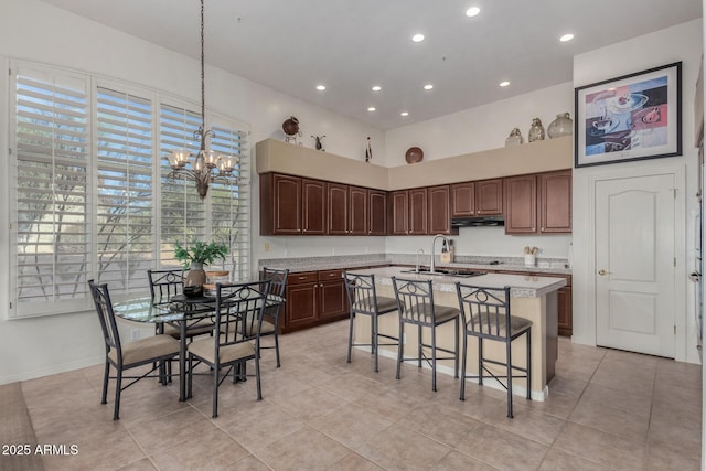 kitchen featuring under cabinet range hood, an inviting chandelier, light tile patterned floors, and recessed lighting