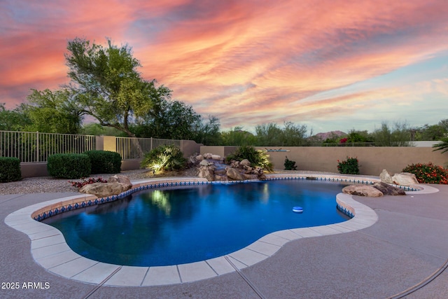 pool at dusk with a fenced backyard and a fenced in pool