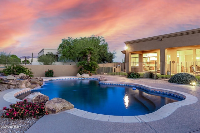 pool at dusk with a fenced in pool, a patio, and fence