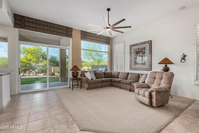 tiled living area featuring a wealth of natural light, visible vents, baseboards, and a ceiling fan