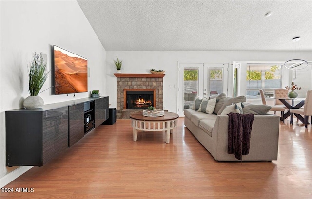 living room with vaulted ceiling, a textured ceiling, and light hardwood / wood-style flooring